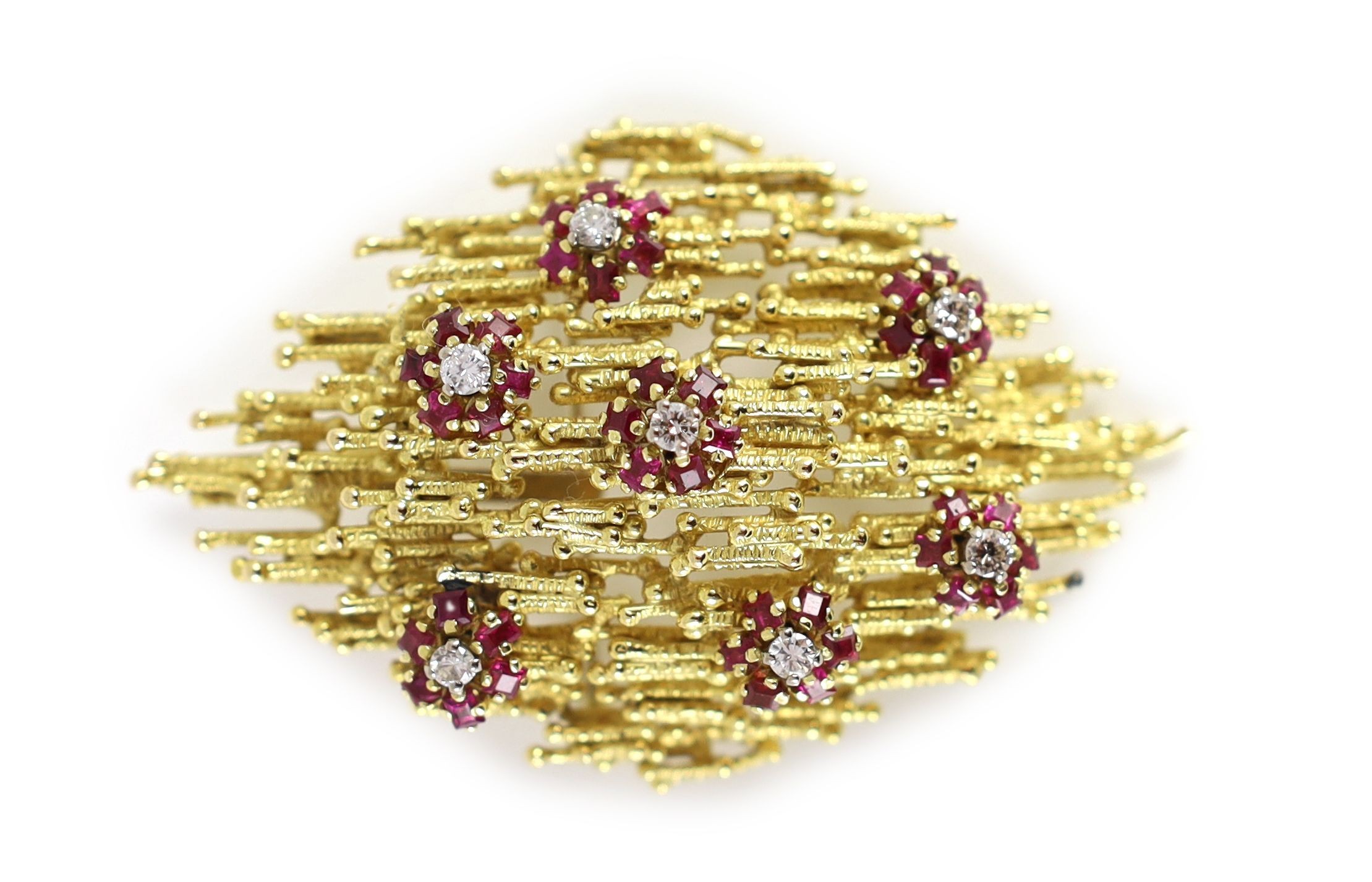 A 1970's textured gold, ruby and diamond cluster set modernist pendant brooch, in the manner of Andrew Grima